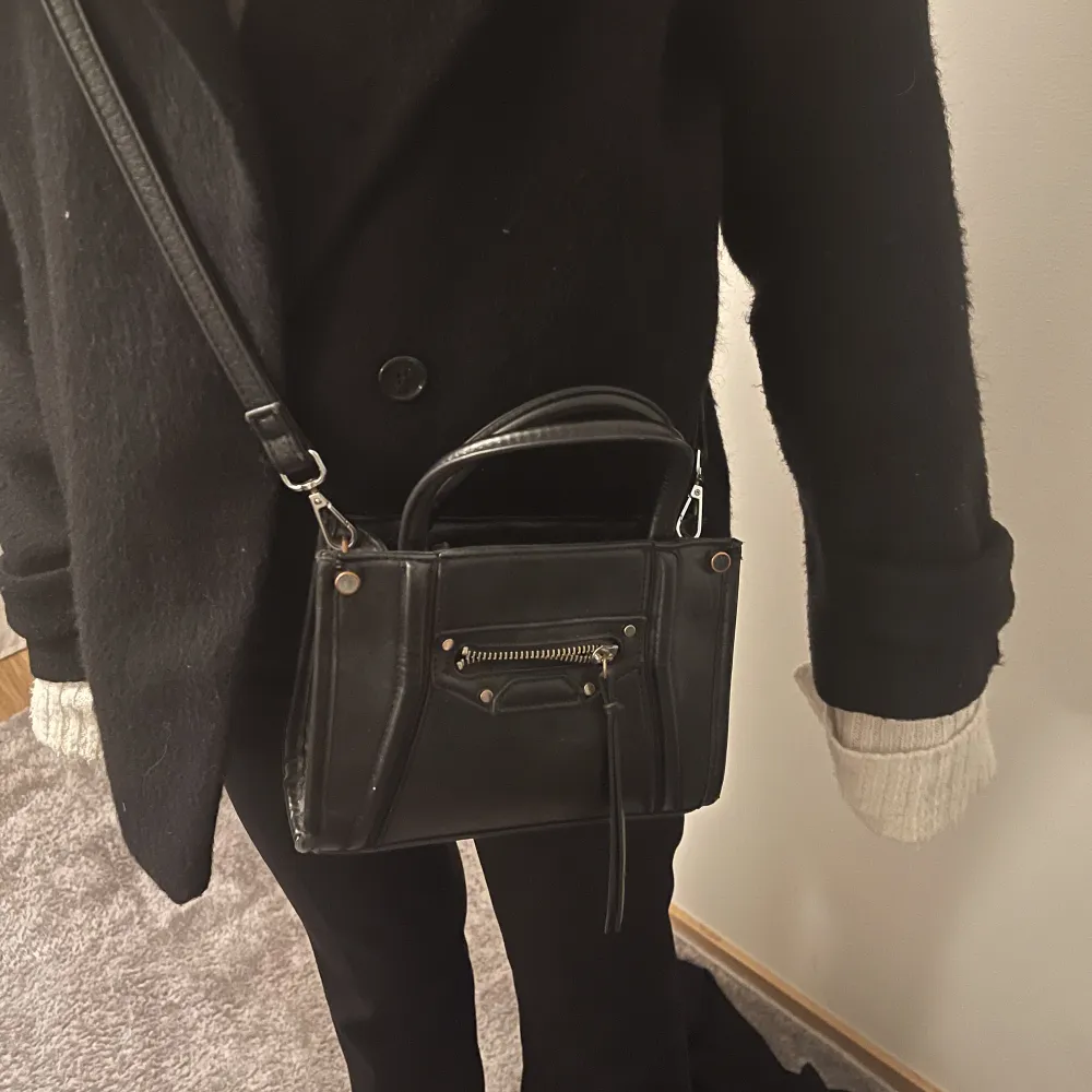 Säljer denna svarta väska då den inte kommer till användning längre. Den är använd vilken syns lite på silvret men är ändå i ett bra skick!. Väskor.