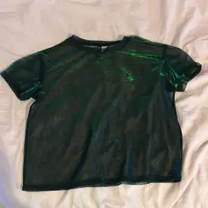En mörkblå/grön skiftande t-shorts i mesh material från H&M Divided i strl S. Den är ganska loosefit