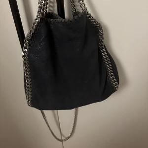 Stella McCartney väska - Säljer nu min Stella McCartney väska i modellen falabella i den marinblåa färgen. Väskan är väl använd men fortfarande i bra skick. Älskar verkligen denna väska och den passar till allt. Dustbag och äkthetsbevis finns. Se defekter på sista bilderna💗💌🫶🏻