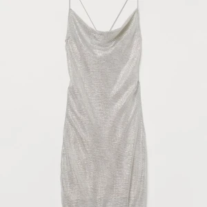 Metallic skimrande klänning - Kort klänning metallic, skimrande silver, draperad ringning fram och tunna axelband som är korslagda i ryggen. Den är fodrad med beige / nude tyg under  Storlek XS / 32 