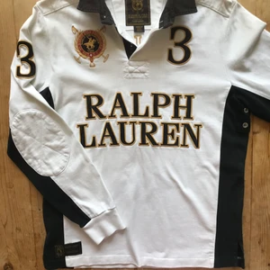 Ralph Lauren Polo pikétröja, vit med detaljer i svart och guld, herr M - Ralph Lauren Långärmad RL- bomullspiké i underbar, tjock, mjuk kvalitet.  Vit med detaljer i svart och guld.  Cool detalj med ventilationshål under armen.  Stl herr medium.  Superfint skick, nästan aldrig använd, 10/10