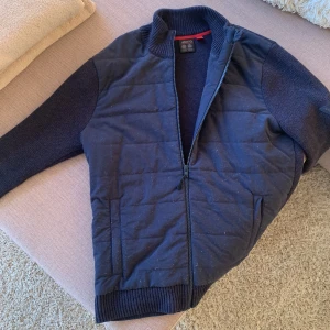 Musto stickad tröja  - Marinblå hybrid jacka/tröja storlek M från musto. Nypris 2500kr sang att produkten är i väldigt fint skick. Använd mindre än 10 gånger. Material ”stickat”.  