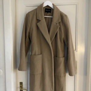 Ullkappa - Så snygg mörkbeige/brun ullkappa med bälte som når till vaderna på mig som är 173. Lite nopprig men annars bra skick! 