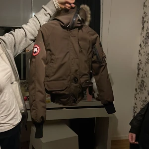 Canada Goose jacka  - En väldigt fin Canada Goose jacka i en fin brun färg, jätte bra skick 10/10.  Använd få gånger.  Hör av er om fler funderingar om jackan, buda på jackan genom att skicka till mig!