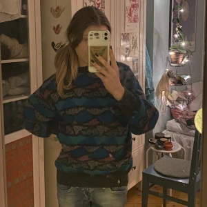 Färgglad stickad tröja - Stickad tröja i blått, turkost, lila och svart! I bra skick förutom ett litet hål i tyget vid den vänstra ärmmudden, fråga för bild! Det står att den är i stl M men jag skulle snarare säga S, passar även xs💜