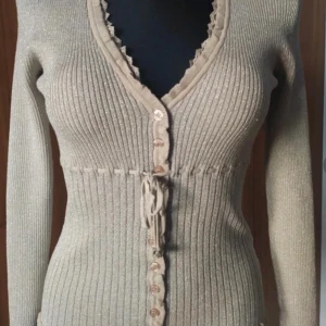 Långärmad topp med knäppning och knytning från Isabelle Kristensen  - Beigaktig topp från Isabell Kristensen med glitter. Storlek S, som ny💕