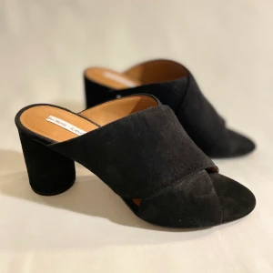 Högklackade Mules ”&otherstories” strl 39 - Slip in högklackade skor från &otherstories. Svart mocka. Använda endast inomhus enstaka gånger. Mycket bra skick. Supersköna att gå i, mjuka och lagom höjd på klack.