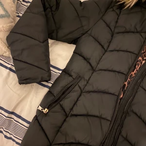 Vinterjacka  - Nytt pris 900kr, frakt= 69kr. Andvänts i 3 månader, varm, tjock och är i medellängd. Kan ta bort luvan och finns en ficka på insidan tillsammans med 2 andra fickor på utsidan. Insidan har ett leopard mönster. OBS dragkedja trasig (se 3:e bild). 