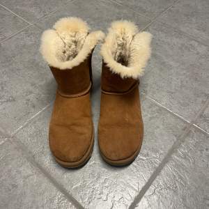 Uggs i storlek 40 med beige fluff och rosett baktill. Använda fåtal gånger, så de är i bra skick! 