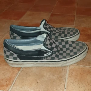 SVART/GRÅ CHECKERD VANS - Slipon Vans. Rutiga svart/gråa skor i bra skick.