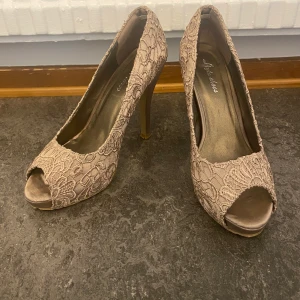 Klackskor  - Klackskor i st 38. Finns i champagne brunfärg eller i svart färg. Klackarna har spets och är i mycket gott skick. 