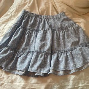 Blå volang kjol - Jag säljer min ljusblåa volang kjol med små vita blommor på. Jag säljer den för att den inte kommer till användning längre💓 INTE  trasig eller fläckig.🫶🏻 Storlek Xs men passar på mig som har storlek S pga att den är stretchig💓