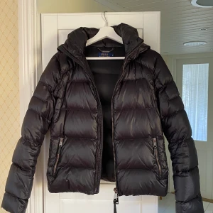 Dunjacka Polo Ralph Lauren - Säljer pga tyvärr vuxit ur den. Mycket bra skick. Halvglansig svart färg och true to size. Logga på ena ärmen som syns i 3e bilden. 