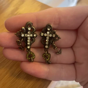 kors örhängen - supercoola kors örhängen som tyvärr inte kommer till användning 🫶det hänger två små hjärtan och ett litet ankare från örhängena oxå😊