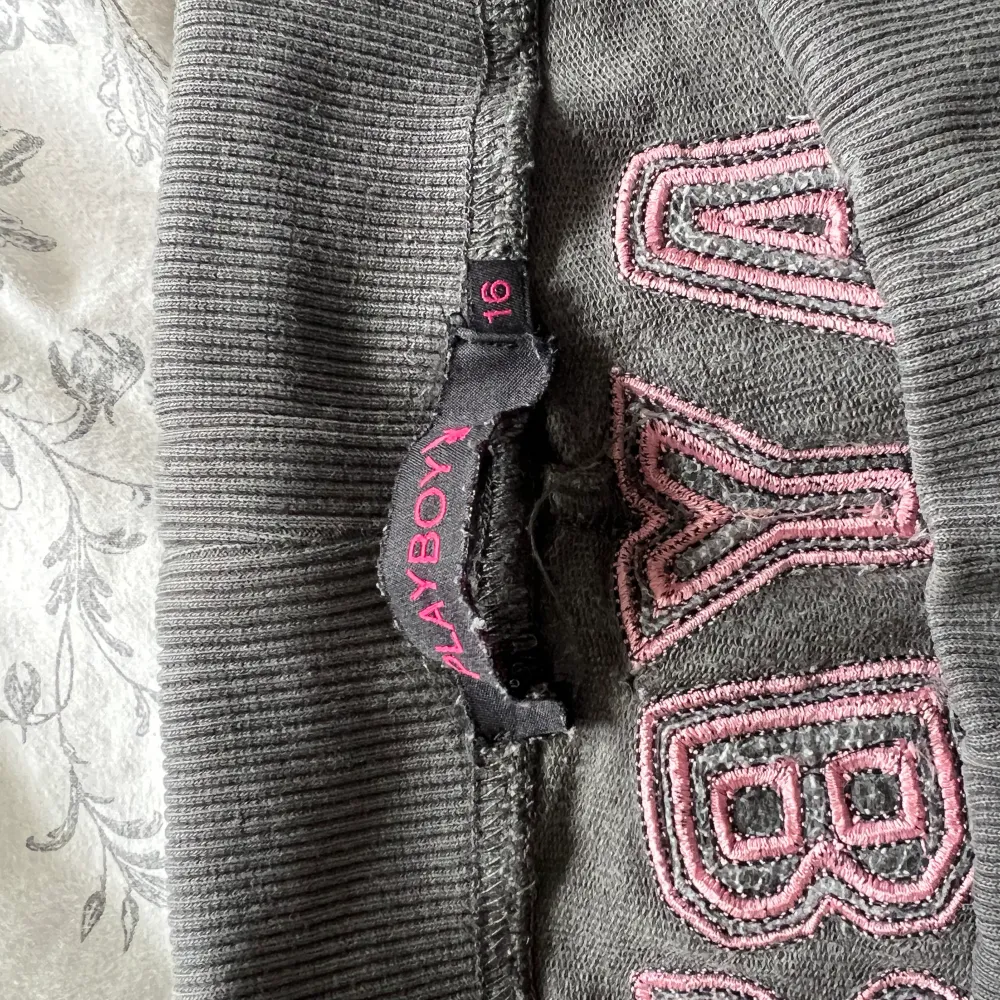 Ett par mörkgråa Playboy byxor, med rosa detaljer. . Jeans & Byxor.