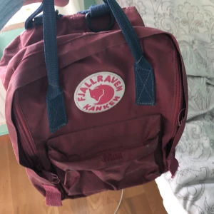 Kånken mini - En röd konken mini! Köpt för 800kr! Säljer för 150kr+frakt! Är i okej skick och har strykt för mitt namn och telefonnummer.