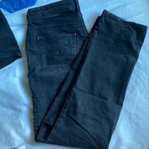 Unika jeans med stjärndetaljer - Ett par skitsnygga svart/gråa jeans från Mac i modellen Melanie. Storlek 40 (Eu) eller 34/32 (US). Stretchigt material och färgen är lite urtvättad. På jackfickorna är det små stjärnor. Kommer tyvärr inte till användning och midjan är mellan/hög.
