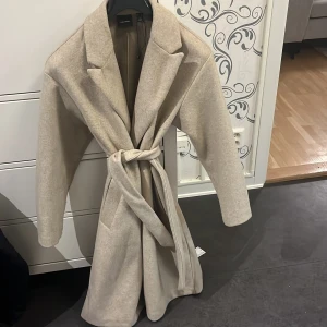 Beige kappa - Beige lång kappa, oversized. Något nopprig som dessa typer av kappor kan bli, men annars fint skick.