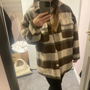 Rutig skjortjacka - En rejäl vadderad skjortjacka i rutigt mönster med bruna nyanser. Är varmt material och bra skick