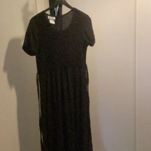 Svart klänning 6 - Fin lång creppklänning med smock i livet och slitsar i nederkant. Köpt vintage.