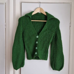 Ärtgrön kofta VINTAGE  - Underbar kofta med ballongärm, v-ringning och krage. Gröna blom-knappar. Passar gissningsvis XS/S/M. Stretchig på bredden. Tjockt och mjukt garn, troligtvis i syntet eller syntetblandning. 