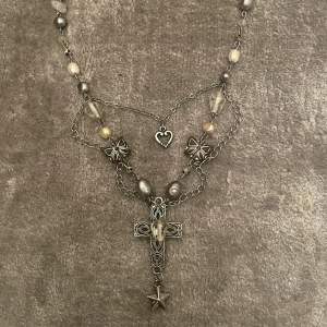 Egentillverkat halsband med ett kors fram.