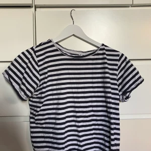 En randig T-Shirt. Svart tröja  - En randig t-Shirt. Svart trekvartstopp