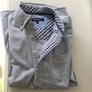 Peckott skjorta ,storlek medium .randig med marinblå färg .länd på skjorta ca 73 cm, bred  ca 51 cm 