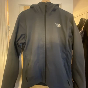 North face regnjacka - Litet hål på ryggen längst ner på jackan, se bild 3.