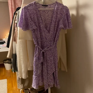 Lila klänning  - Lila klänning med blommönster. Aldrig använd, fint skick!