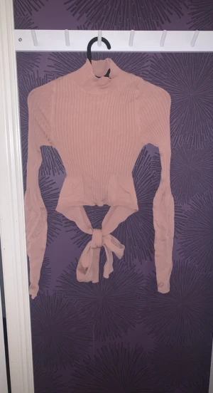 Stoickad knytbar topp - En stickad knytbar topp med långa armar och i stretchigt material. Med en polokrage