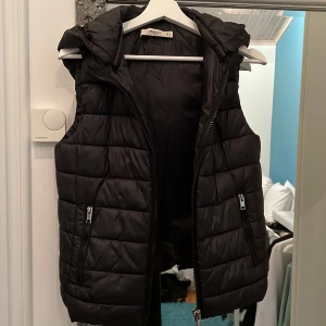 Väst - Svart tunnare dunväst med avtagbar luva från Mango. Använd men fint skick i storlek S. 
