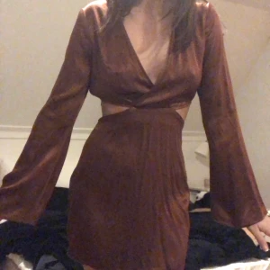 Cut out klänning  - Superfin bronsfärgad långärmad cut out klänning från pull&bear! Färgen stämmer mest på den tredje bilden. Använd en gång så i princip nyskick! Har vida armar. Är i storlek M men skulle mer säga den är S. Den är så fin men har många liknande så får tyvärr sälja. Köparen står för frakten💕 priset kan oftas diskuteras och kan även ge paketpris så kika gärna in de andra jag säljer