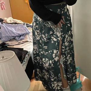 Långblommig kjol - En grön lång blommig kjol från Shein i storlek 38. Omlott och ger därför en slits på ena benet. Super skön och band i midjan för att knyta hårdare/lösare.
