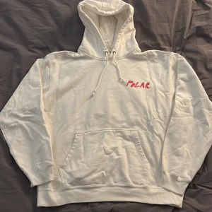 Vit polar hoodie med tryck på ryggen  - Säljer min vita polar hoodie i väldigt bra skick. Hoodien med tryck är även sällsynt och ganska svår o få tag på. Ordinarie pris är 1000 kr.  Kan även tillägga att storleken är i Large men hoodien är ganska kort i midjan och armar.