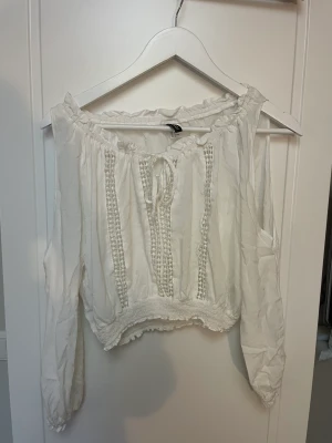 Vit blus med hål för axlarna  - En vit blus med hål vid axlarna, några år gammal men väldigt fint skick. Strl. 38 men skulle även säga att den passar 36