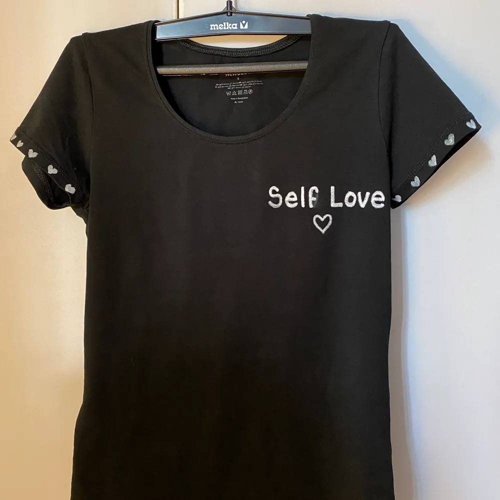 En vanlig tshirt från newbody med ditmålat tryck ”selflove” och hjärtan på träjärmarna. T-shirts.