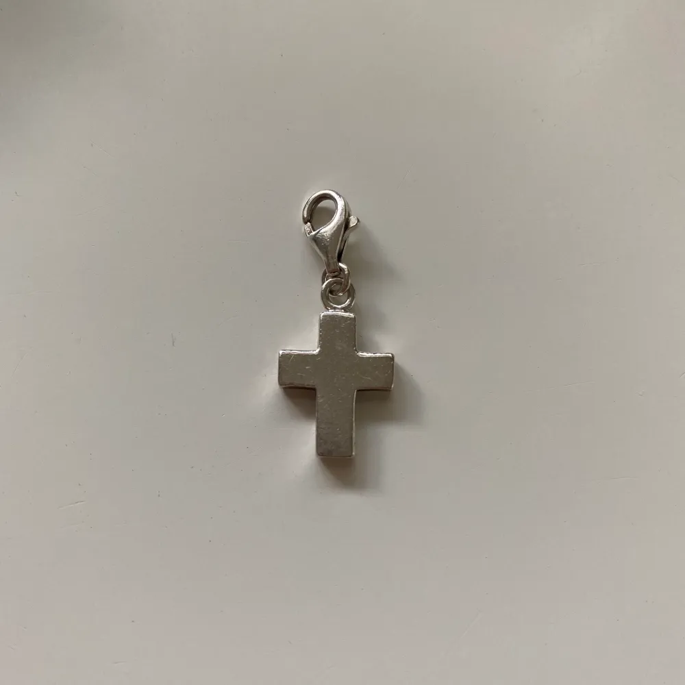 En berlock från Thomas Sabo i from av ett kors. Hela smycket är ca 2,6 cm. Smyckets skick syns bäst på bild 2. En smyckesbox medföljer, om man vill ha den, men jag har målat boxen inuti svart, se bild 3. Säljer för 100kr + 13 kr frakt (51kr spårbar). Accessoarer.