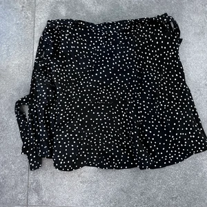 Svart kjol med vita prickar från Zara - Svart vit kjol från Zara med knytdetalj i midjan. Säljer pga av den är för liten. Slutsåld! 