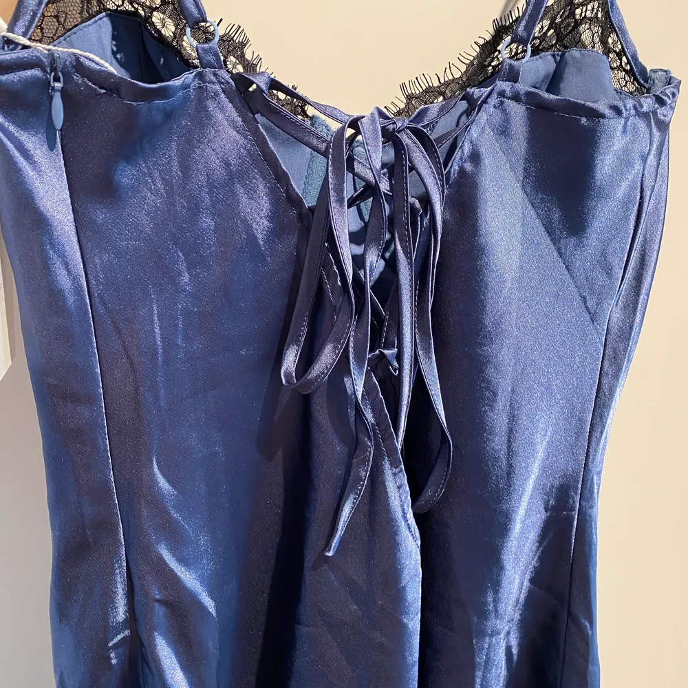 Aldrig använd mörkblå klänning som slutar ovanför knäna, med svart spets och knytning i ryggen. . Klänningar.
