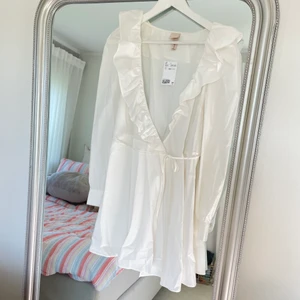 Vit omlottklänning - Vit omlottklänning med volanger från HM. Storlek 36. Helt ny prislappen är kvar. Orginalpris 399kr