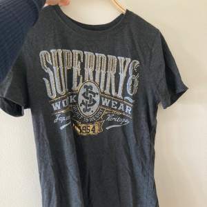 Säljer denna jättefina tshirt med tryck från superdry! Guldet på trycket är metalliskt o texten ljusgrå/blå Jätteskönt material och aldrig använd!!🥰 (Nypris 340kr)