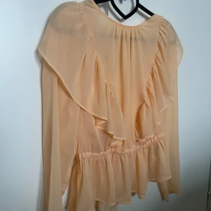 Blus med volanger - Blus med volanger, i en ljus orange färg. 
