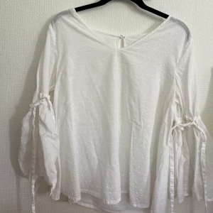 Vit blus  - En vit blus med ett prickigt mönster, vida ärmar, v-ringad halskrage! Band att dra åt med vid ärmarna! Jag har klippt bort lappen så vet ej storlek, men jag bär i vanliga fall S så skulle säga storlek xs-m. 