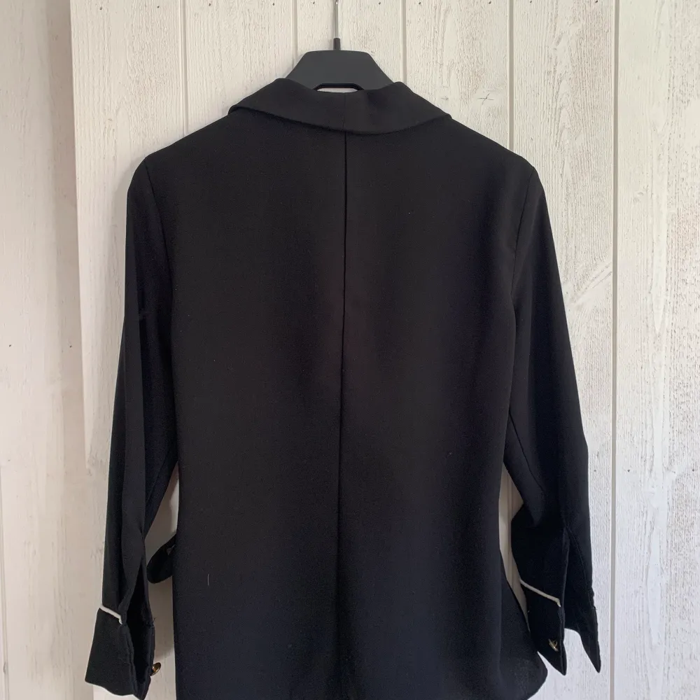 Säljer min svarta omlottskjorta/blus i storlek S från zara! Den är använd men i fint skick. Ärmen är kortare och är snygg att vika upp och har ett band att knyta i sidan. Hör av dig om du har frågor!☺️. Skjortor.