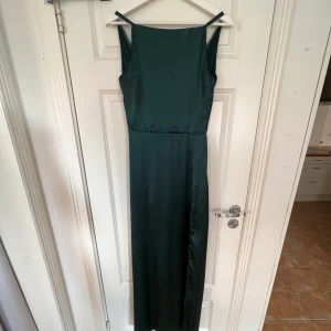 Mörkgrön Balklänning - Säljer min balklänning, endast använd 1 gång. Den har en slits på vänster sida. Strl 34 från Bubbleroom