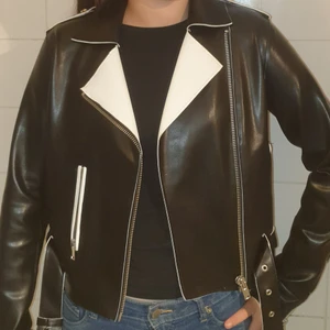 MC-jacka syntetskinn - Oanvänd syntetjacka i MC-modell, avart med vita detaljer. Rätt plastig i känslan men mjuk och följsam. Ganska stor strl 34. Modellen är strl S och 163 cm. lång. 