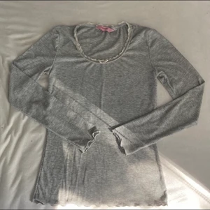 Grå tröja - Säljer denna gråa långärmade tröja med spets detalj och en liten rosett på urringningen, har inga synliga defekter, men kommer inte till användning. Min byst är ca 79cm