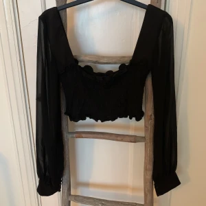Smockad croptop från Chiquelle strl M - Använd en gång. Jättefint skick! Så fin top med långa ärmar i transparent luftigt tyg. Bystdelen är smockad. 