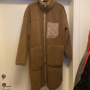 Lång teddyjacka  - Brun teddyjacka från H&M, produktnummer 0991731 Längd: 106cm Ärm: 52,4cm Axel: 64cm
